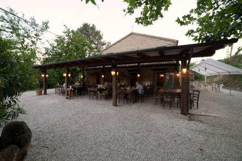 Buiten eetgelegenheid bij Camping Podere Sei Poorte in Marche, Italië, omgeven door groen.