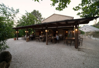 Buiten eetgelegenheid bij Camping Podere Sei Poorte in Marche, Italië, omgeven door groen.