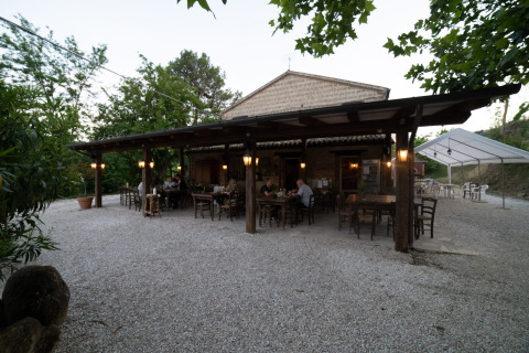 Outdoor dining area at Camping Podere Sei Poorte holiday park in Marche, Italy, surrounded by greenery.
