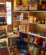 Una variedad de comestibles, vino y productos frescos en una pequeña tienda del Camping Les Sapins, Occitanie, Francia.