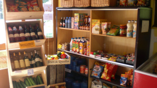 A variety of groceries, wine, and fresh produce displayed in a small shop at Camping Les Sapins, Occitanie, France.