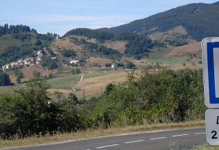 Vejskilt til Camping Les Sapins, feriepark i et bakket landskab i Occitanie, Frankrig, 2000 meter væk.