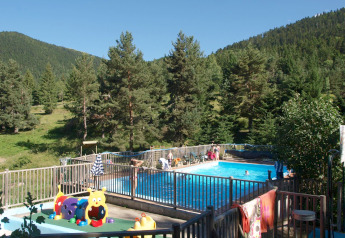 Piscina exterior en Base Lodge, Camping Les Sapins, rodeada de montañas y bosque en Francia.