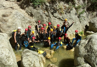 Groep kampeerders met helmen en wetsuits op avontuur bij Camping Les Sapins in Occitanie, Frankrijk.