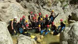 Group of campers wearing helmets and wetsuits on a canyoning adventure at Camping Les Sapins, Occitanie.