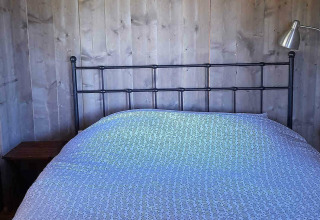 Schlafzimmer im Safarizelt Base Lodge auf Camping Les Sapins in Frankreich mit Doppelbett und Lampe.