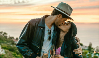Una pareja se besa al atardecer cerca de Treviso, Italia, sosteniendo copas de champán en la naturaleza.