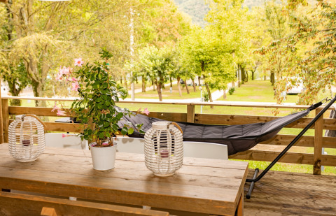 Terrazza esterna con tavolo in legno, piante e amaca al Camping Al Lago di Lago, Italia.