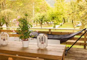 Buitenterras met houten tafel, planten en hangmat bij Camping Al Lago di Lago, Italië.