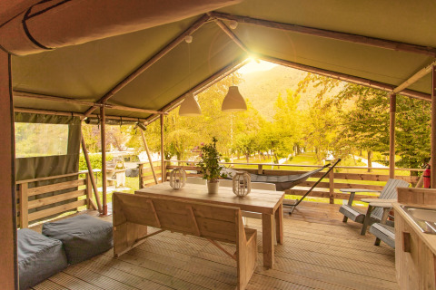 Veranda coperta della tenda safari Wood Lodge con tavolo di legno al Camping Al Lago di Lago, Italia.