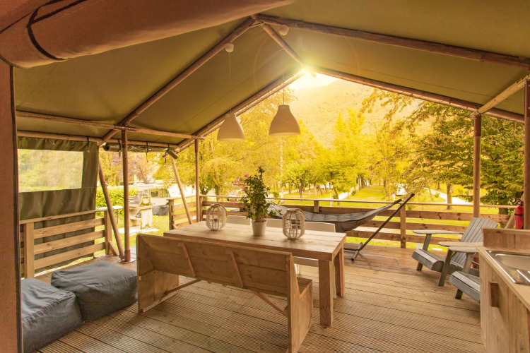 Innenbereich des Safari-Zeltes Wood Lodge mit Holztisch und Aussicht auf Camping Al Lago di Lago, Italien.