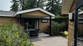 Udendørs terrasse og indgang til Family Lodge med spabad på De Thijmse Berg, omgivet af grønne planter.
