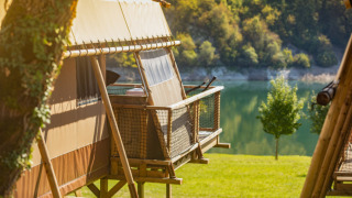 Tienda safari Desert Lodge XL con vistas al lago y naturaleza verde, perfecta para una escapada tranquila.