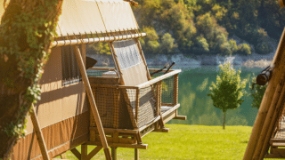 Tenda safari Desert Lodge XL con vista sul lago e paesaggio verde, perfetta per soggiorni nella natura.