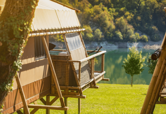 Safari-tent Desert Lodge XL uitkijkend op een meer en groen landschap, perfect voor een natuurvakantie.