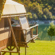 Safari-telt Desert Lodge XL med udsigt over en sø og grønne træer, perfekt til naturophold.