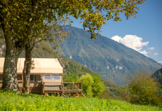 Udsigt til Desert Lodge XL safaritelt ved Camping Gajole i Italien, omgivet af bjerge og grønne træer.
