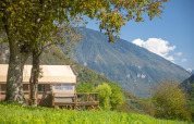 Carpa safari Desert Lodge XL en Camping Gajole, Italia, rodeada de montañas verdes y naturaleza exuberante.