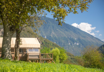 Carpa safari Desert Lodge XL en Camping Gajole, Italia, rodeada de montañas verdes y naturaleza exuberante.