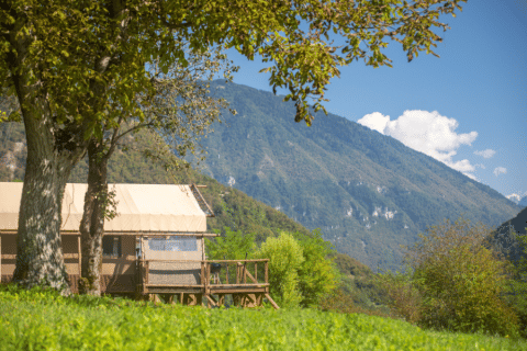 Desert Lodge XL Safarizelt auf Camping Gajole in Italien mit Blick auf grüne Berge und blauen Himmel.