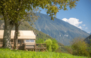 Desert Lodge XL safari tent at Camping Gajole in Italy, surrounded by lush greenery and scenic mountains.