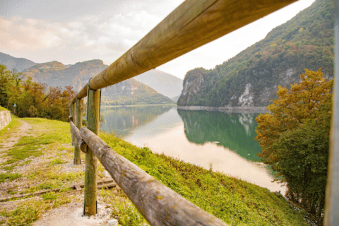 Lake and mountain view at Camping Gajole in Veneto, Italy, with nature trail and rustic wooden railing.