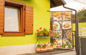 Udendørs scene på Camping Gajole i Veneto, Italien med grøn væg, vindue og italiensk madmenu.