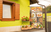 Buitenscène bij Camping Gajole in Veneto met groene gevel, houten raam en menubord van gerechten.