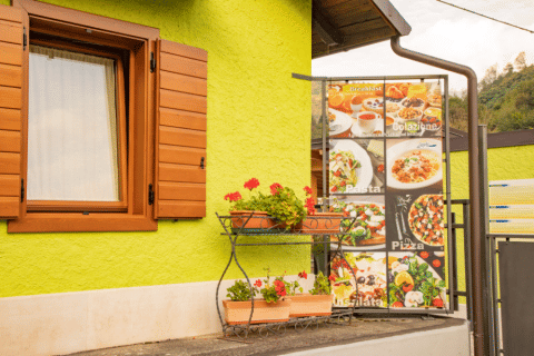 Outdoor view at Camping Gajole in Veneto, Italy with green wall, wooden window and food menu sign.