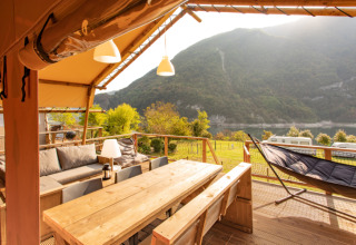 Terraza de madera de la tienda Desert Lodge XL en Camping Gajole, Italia, con vistas al lago y las montañas.