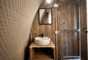 Innenaufnahme des Safari-Zeltes Big Oak Lodge mit Holzwänden, rundem Waschbecken und Spiegel.