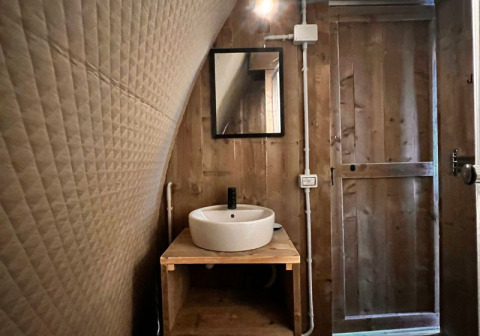 Interieur van het Big Oak Lodge safaritent met houten muren, ronde waskom en spiegel boven de wastafel.