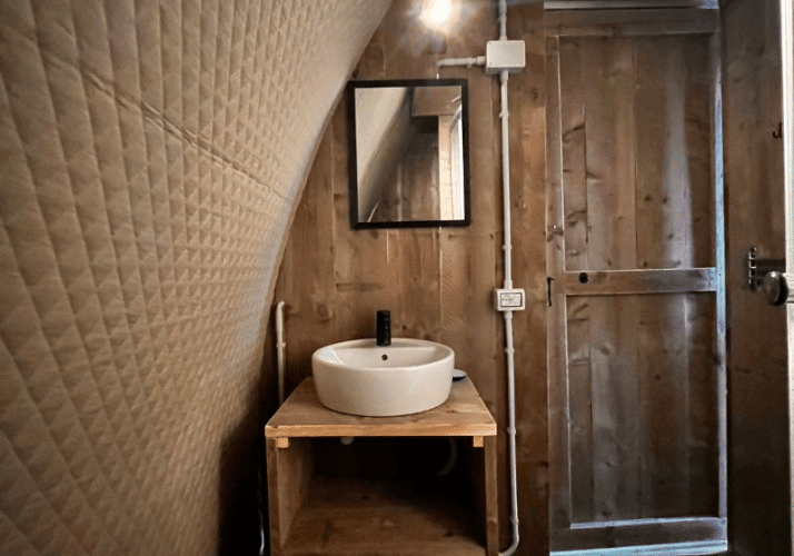 Interior photo of Big Oak Lodge safari tent featuring wooden walls, round basin, and mirror above sink.
