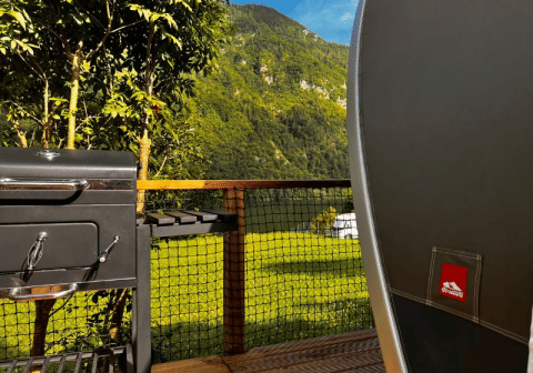 Vista dalla tenda safari Big Oak Lodge con barbecue, terrazza e colline verdi sullo sfondo.