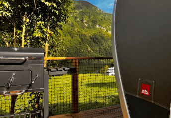 Blick aus dem Safari-Zelt Big Oak Lodge mit Grill und Terrasse vor grünen Bergen und Wäldern.