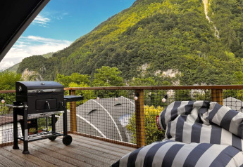 Udendørs terrasse på Big Oak Lodge ved Camping Gajole i Italien med grill, sækkestol og bjergudsigt.