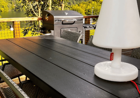 Área de comedor exterior en la tienda safari Big Oak Lodge con parrilla, sillas y una lámpara blanca grande.