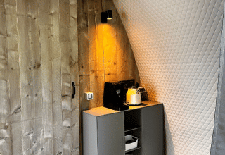 Rincón de la tienda safari Big Oak Lodge con pared de madera, cafetera, tetera y luz suave.