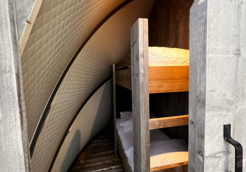 Binnenzicht van de Big Oak Lodge safaritent, met stapelbedden en gebogen, gevoerde muren.