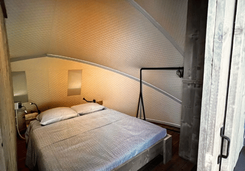 Dormitorio en la tienda safari Big Oak Lodge con cama doble, paredes de madera y ambiente acogedor.