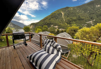 Terrasse vom Big Oak Lodge, Camping Gajole in Italien mit Grill, Liegekissen und Blick auf die Berge.