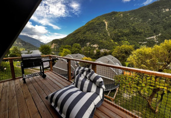 Terrasuitzicht bij Big Oak Lodge, Camping Gajole in Italië met barbecue, ligzetel en berglandschap.