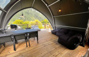 Intérieur d'une tente safari au Big Oak Lodge avec table à manger, canapés et vue sur la montagne.