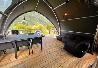 Safari teltinteriør ved Big Oak Lodge med spisebord, loungestole og naturskøn udsigt over skove.