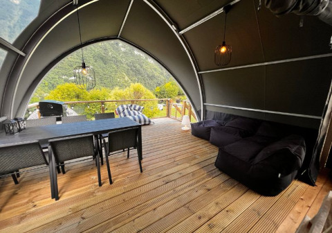 Interieur van safaritent aan Big Oak Lodge met eettafel, loungezetels en uitzicht op bergen.