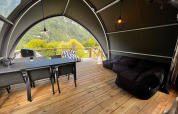 Interieur van safaritent aan Big Oak Lodge met eettafel, loungezetels en uitzicht op bergen.