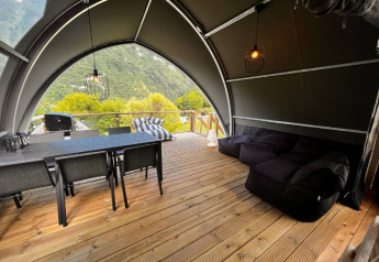 Interno di tenda safari al Big Oak Lodge con tavolo da pranzo, divani e vista sulle montagne verdi.