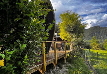 View of the Big Oak Lodge safari tent, surrounded by lush trees and mountains under a striking sky.