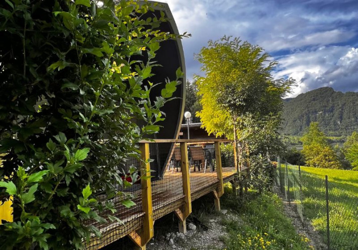 View of the Big Oak Lodge safari tent, surrounded by lush trees and mountains under a striking sky.