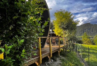 Vista de la tienda safari Big Oak Lodge, rodeada de árboles verdes y montañas bajo un cielo impactante.